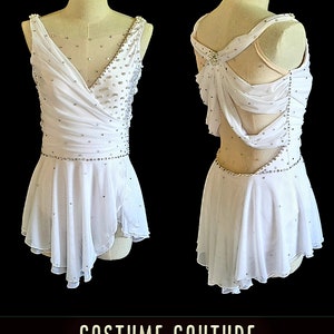 Puede incluir: Traje de patinaje art&iacute;stico blanco con un dise&ntilde;o de espalda cruzada y una falda con un volante de capas. El traje est&aacute; decorado con pedrer&iacute;a. "SAMPLE CUSTOM DESIGN" y "COSTUME COUTURE by Naomi" est&aacute;n escritos en la imagen.