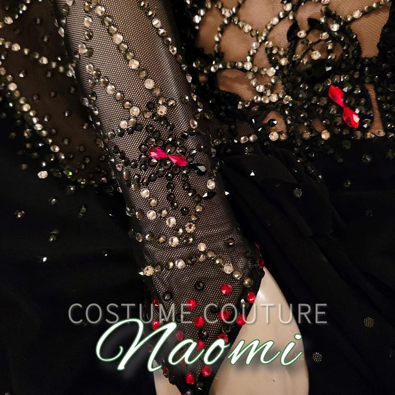 Puede incluir: Traje negro con intrincado trabajo de cuentas y detalles rojos. El dise&ntilde;o presenta una manga transparente adornada con cuentas brillantes y adornos rojos. El texto "COSTUME COUTURE Naomi" es visible.