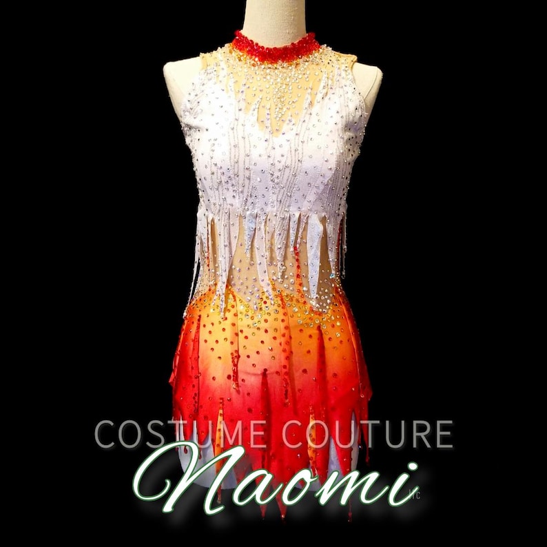 K&ouml;nnte beinhalten: Ein wei&szlig;es und rotes Tanzkost&uuml;m mit Fransen und einem Farbverlauf. Das Kost&uuml;m ist mit Strasssteinen verziert und hat einen hohen Ausschnitt. Der Text "Costume Couture Naomi" ist am unteren Rand des Bildes sichtbar.