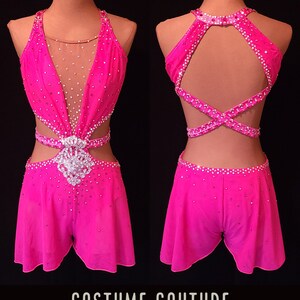 Puede incluir: Un traje de baile rosa con escote halter, un panel transparente y una espalda cruzada. El traje est&aacute; adornado con pedrer&iacute;a y tiene una falda corta. "SAMPLE CUSTOM DESIGN" y "COSTUME COUTURE by Naomi" est&aacute;n impresos en la imagen.