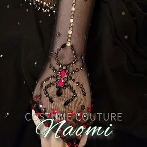 Puede incluir: Guante de malla negro con un dise&ntilde;o de ara&ntilde;a hecho de pedrer&iacute;a negra y roja, con abdomen rosa. El texto "COSTUME COUTURE Naomi" es visible. El guante est&aacute; adornado con pedrer&iacute;a adicional.
