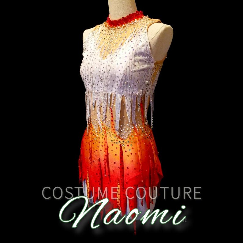 K&ouml;nnte beinhalten: Ein wei&szlig;es und rotes Tanzkost&uuml;m mit einem Fransenrock und Strasssteinen. Das Kost&uuml;m befindet sich auf einer Schaufensterpuppe vor schwarzem Hintergrund. Der Text "Costume Couture Naomi" befindet sich am unteren Rand des Bildes.
