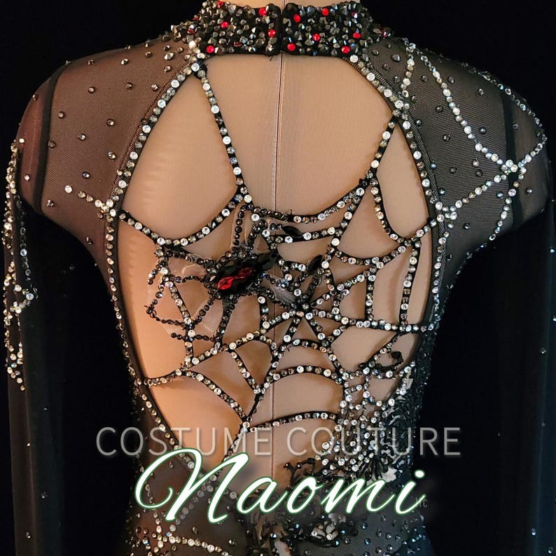Puede incluir: Traje negro con dise&ntilde;o de telara&ntilde;a en la espalda, adornado con pedrer&iacute;a y una ara&ntilde;a. El cuello alto y la espalda con abertura est&aacute;n adornados con gemas rojas y negras. El texto "COSTUME COUTURE Naomi" es visible.