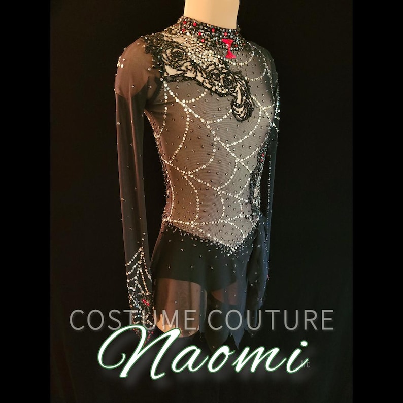 Puede incluir: Vestido de patinaje art&iacute;stico negro con mangas largas y cuello alto. El corpi&ntilde;o presenta un dise&ntilde;o de telara&ntilde;a con adornos blancos y rojos. El texto "COSTUME COUTURE Naomi" se muestra en la parte inferior.
