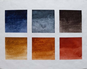 May include: A watercolor paint swatch card with six squares showing different shades of blue, gray, brown, yellow, orange, and red.