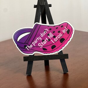 Puede incluir: Una pegatina de zapato Croc rosa y morado con lunares negros. La pegatina tiene el texto "The party don't start till I croc in!" impreso en ella.