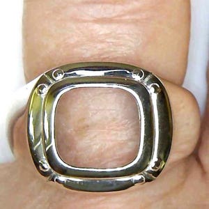 May include: A white ceramic mug with a black handle and the text "But First, Coffee" in a bold, black font. The mug is set against a blurred background, suggesting a cozy setting.