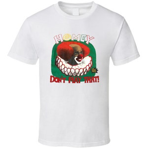 Puede incluir: Camiseta blanca con una ilustración roja, blanca y verde de un payaso con el texto "Homey Don't Play That!"