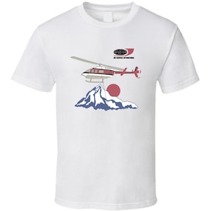May include: White t-shirt with a graphic of a red and white helicopter flying over a mountain with a red sun in the background. The text "Air Services International" is above the helicopter.