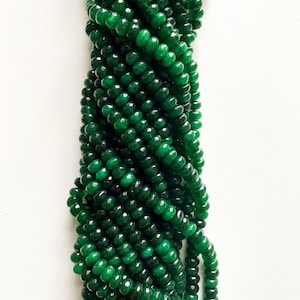 May include: A strand of dark green jade beads, each bead is faceted and has a rounded shape.
