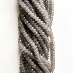 May include: A strand of gray faceted glass beads. The beads are round and have a smooth, polished finish.