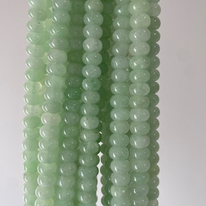 May include: A strand of light green jade beads. The beads are round and smooth, and they are strung on a clear thread.