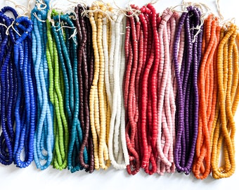May include: A collection of 18 strands of colorful glass beads. The beads are small and round, and they are arranged in a rainbow pattern. The beads are strung on a thin cord.
