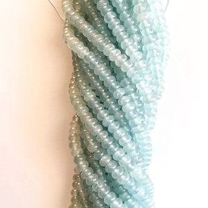 May include: A strand of light blue and green glass beads. The beads are round and have a smooth, polished finish.