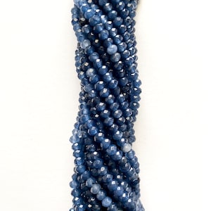 May include: A strand of faceted, deep blue gemstone beads. The beads are small, round, and tightly strung together, creating a textured, rope-like appearance. The color is a rich, dark blue with subtle variations in tone, reflecting light.