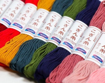 May include: A collection of ten spools of colourful embroidery floss, each labelled with Japanese text and the words "Kogin Thread Cotton 100%". The colours include red, orange, yellow, green, blue, pink, and light pink.