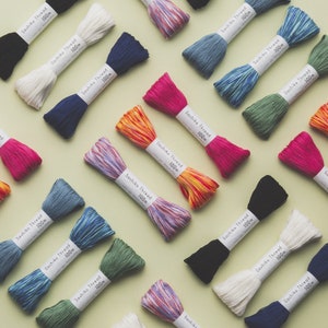 May include: Assortment of colourful Sashiko threads, each skein is 100m long. The threads are arranged in a grid pattern on a light green background.