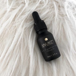 Könnte beinhalten: Eine schwarze Glasflasche mit Tropfer, beschriftet mit "Anuket Luxury Aromatherapy Pure Egyptian Rose Diffusing Oil 10ml / .3 fl oz"