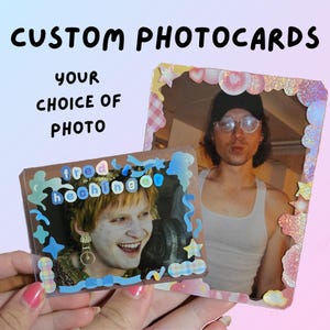 May include: Two custom photocards with photos of people, decorated with stickers. The text "CUSTOM PHOTOCARDS" and "YOUR CHOICE OF PHOTO" are at the top. One photocard has the name "fred heehing" on it.