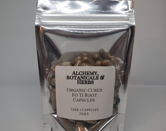 Puede incluir: Una bolsa de cierre hermético plateada llena de cápsulas marrones. La etiqueta dice "ALCHEMY, BOTANICALS & HERBS ORGANIC CURED FO TI ROOT CAPSULES TAKE 2 CAPSULES DAILY".