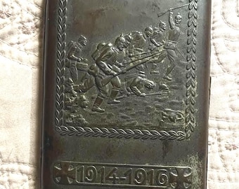 Vintage metal German WW1 cigarette case with trench battle scene.
