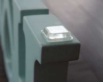 Può includere: Primo piano di una lettera in legno blu chiaro con un cuscinetto adesivo in plastica trasparente sul fondo.