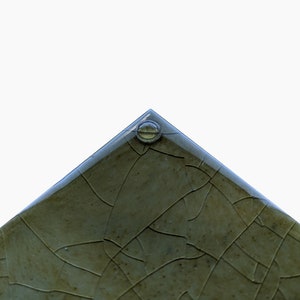 Pu&ograve; includere: Primo piano di una piastrella di ceramica verde con una glassa screpolata e una piccola bolla di vetro trasparente al centro.