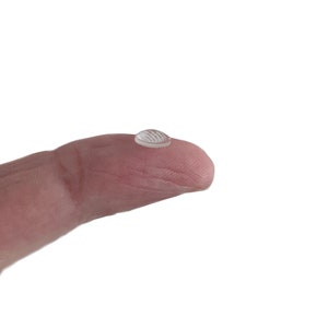 May include: A clear, round drop of liquid resting on a fingertip.