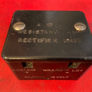 May include: A black Resistance and Rectifier Unit with the text "RESISTANCE AND RECTIFIER UNIT" and "ACCUM" and "WARNING LGT" printed on it. The unit has two screws on top and is labeled "5C/12V" and "12 VOLT".