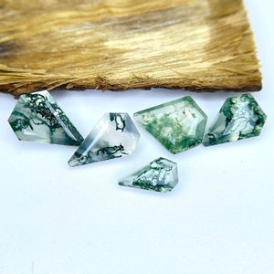 May include: Five green and white moss agate gemstones in a faceted, teardrop shape.