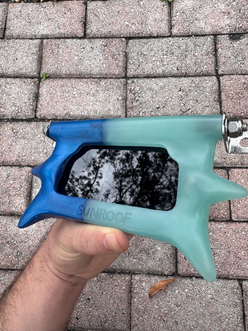 May include: A blue and teal sunroof tool with the word "SUNROOF" printed on the side. The tool has a star-shaped design on the end and a metal hinge.
