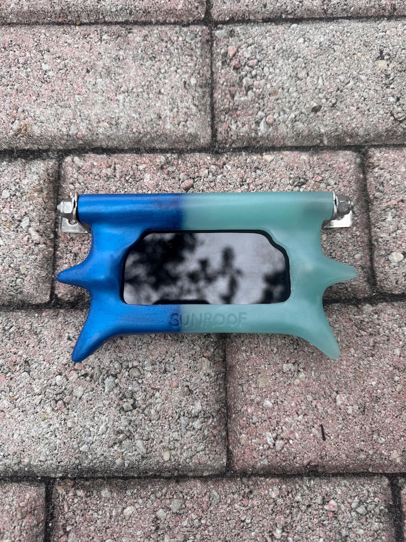 May include: A blue and teal sunroof visor with the word "SUNROOF" printed on it. The visor has a rectangular opening and is made of a durable material. The visor is designed to attach to a vehicle's sunroof.