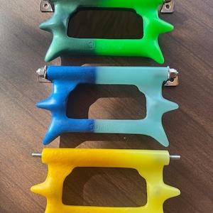 May include: Three colourful, stylised handles with the word "SUNROOF" embossed on each. The handles are green, blue, and yellow, each with a unique gradient effect. They have a distinctive shape with pointed protrusions and metal hardware.