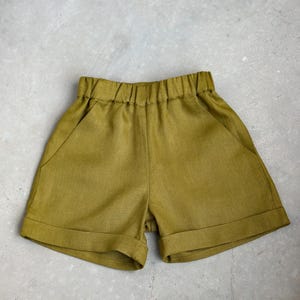 Puede incluir: Pantalones cortos de lino de color verde oliva con una cintura elástica ancha y dobladillos vueltos.