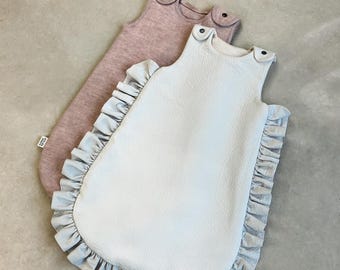 May include: Two baby sleep sacks, one light blue with ruffles and one dusty rose. Both sleep sacks have a sleeveless design.