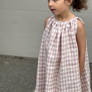 Puede incluir: Un vestido sin mangas de cuadros vichy rosa y blanco con un escote fruncido.