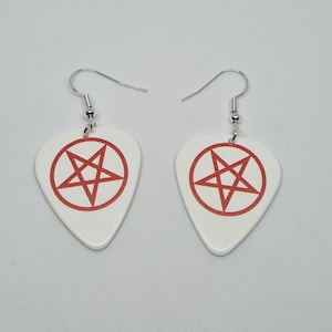 Puede incluir: Un par de pendientes de guitarra blanca con un diseño de pentagrama rojo.