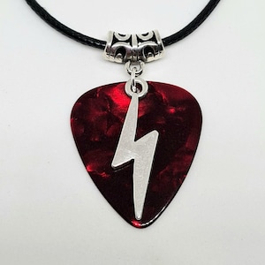 May include: A red guitar pick necklace with a silver lightning bolt pendant. The necklace is made of black leather cord.