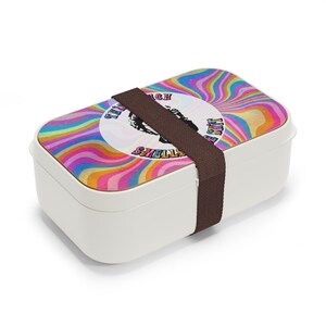 Puede incluir: Fiambrera blanca con un dise&ntilde;o psicod&eacute;lico colorido y una correa marr&oacute;n. El dise&ntilde;o presenta un c&iacute;rculo con el texto "This much smells like a shift".
