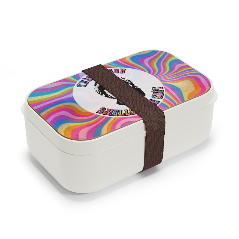 Puede incluir: Fiambrera blanca con un dise&ntilde;o psicod&eacute;lico colorido y una correa marr&oacute;n. El dise&ntilde;o presenta un c&iacute;rculo con el texto "This much smells like a shift".