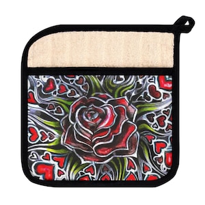 Könnte beinhalten: Ein Topflappen aus beigefarbenem Stoff mit schwarzem Rand, verziert mit einer roten Rose mit schwarzem Umriss und grünen Blättern, umgeben von roten Herzen auf schwarzem Hintergrund.