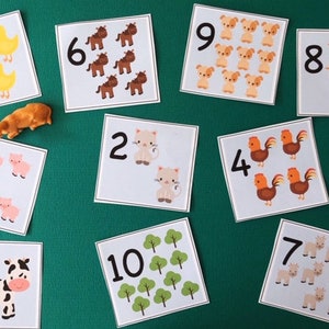 May include: Educational counting cards with farm animal illustrations and numbers 1-10. Includes toy farm animals: a cow, a pig, a duck, a horse, and a cow. The cards feature images of animals and trees, perfect for learning numbers.