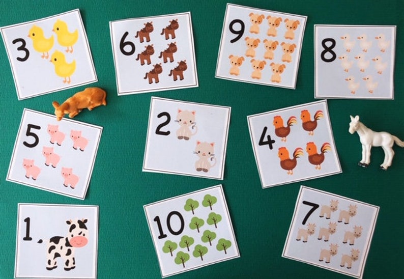May include: Educational counting cards with farm animal illustrations and numbers 1-10. Includes toy farm animals: a cow, a pig, a duck, a horse, and a cow. The cards feature images of animals and trees, perfect for learning numbers.