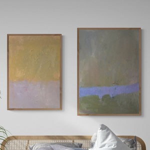 May include: A white linen bed with a wooden headboard and a matching wooden bench at the foot of the bed. Two abstract paintings hang on the wall behind the bed. A potted plant sits on the floor next to the bed.