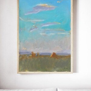 May include: A framed abstract landscape painting with a blue sky, white clouds, and a green field with brown brushstrokes.