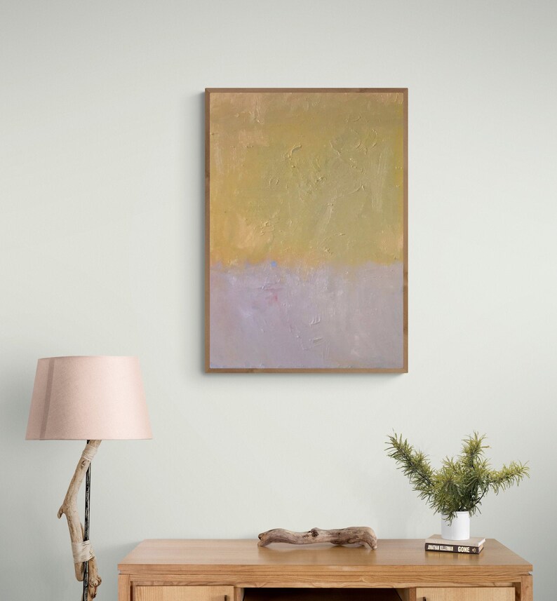 May include: Abstract painting in a wooden frame with a yellow and purple color scheme. The painting is hanging on a white wall above a wooden table.