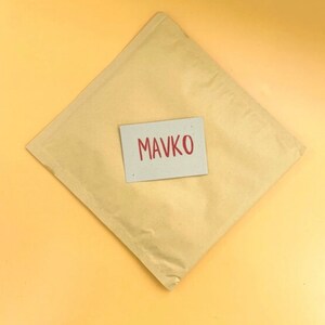 May include: A brown paper envelope with a white card on top. The card has the word "MAVKO" written in red.