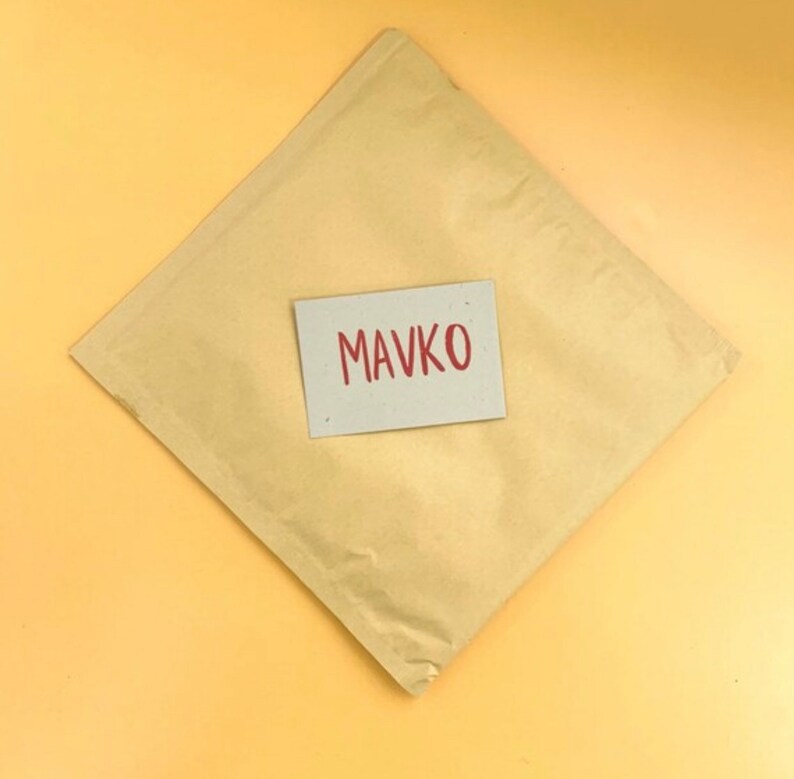 May include: A brown paper envelope with a white card on top. The card has the word "MAVKO" written in red.