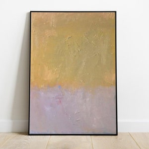 May include: Abstract painting with a textured gold background and a light purple bottom half. The painting is framed in black.