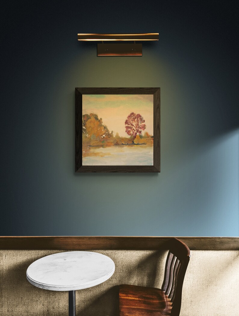 Puede incluir: Una pintura enmarcada de un paisaje con un &aacute;rbol rojo en el centro, colgada en una pared azul con una mesa y una silla de madera marr&oacute;n en primer plano.